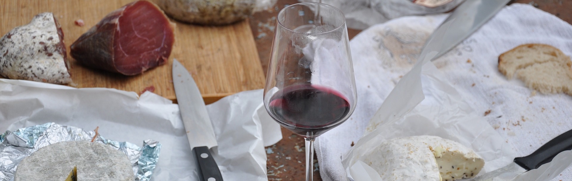 a half-finished board of mixed cheeses, charcuterie, and red wine