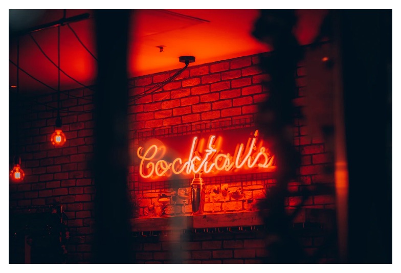 a neon sign reading 'cocktails' above a trendy bar